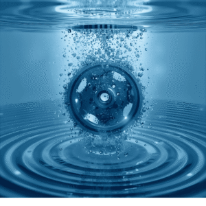 Металлическая шестеренка, погруженная в голубую воду с пузырьками, символизирующими ультразвуковую очистку сложных объектов.